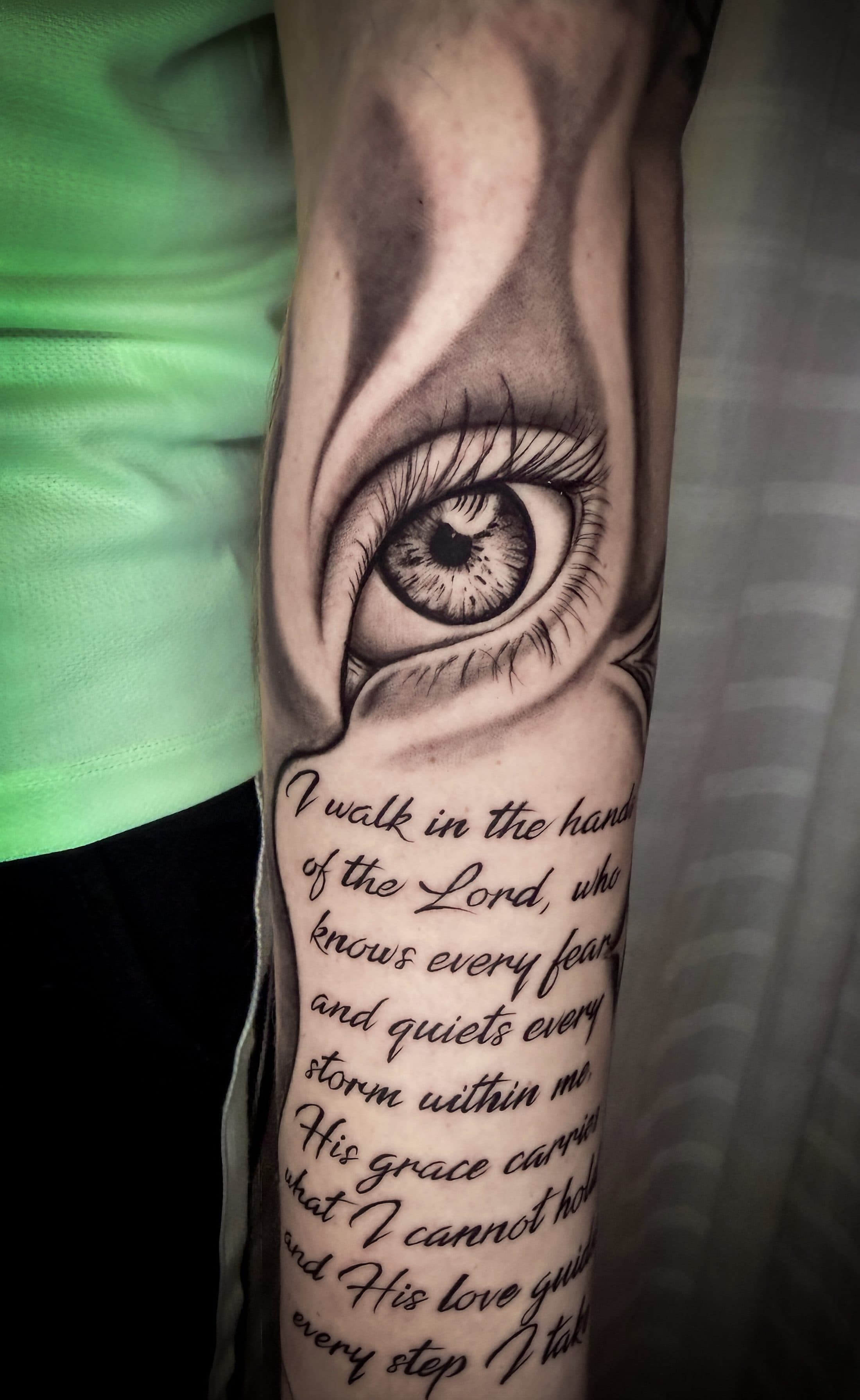 Auge mit Schriftzug, fotorealistisch auf dem Unterarm