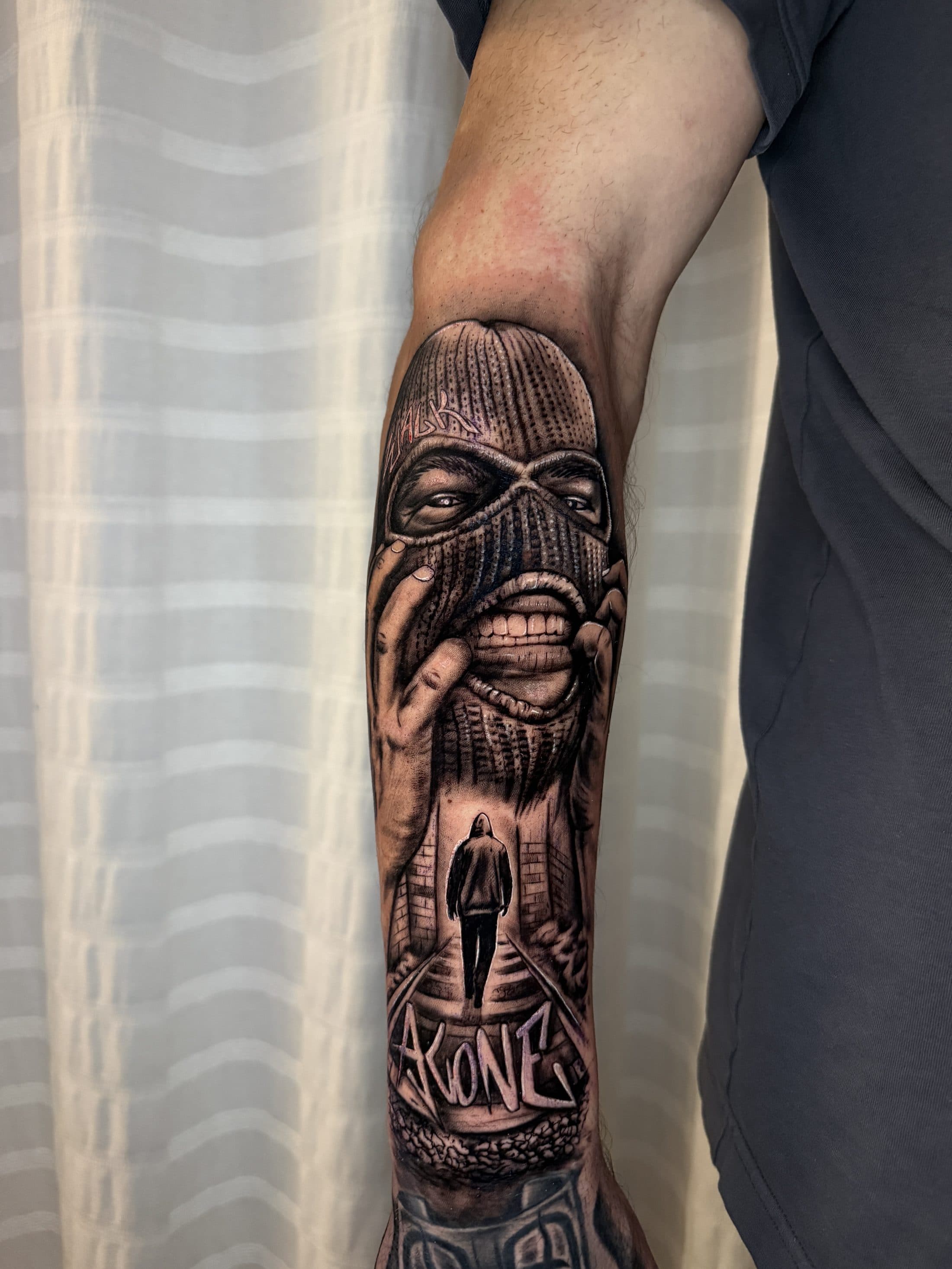 Vermummter Kopf mit Sturmhaube, Kapuzenfigur in einer Gasse und Graffiti-Schriftzug ALONE, Black & Grey Realistic auf dem Unterarm