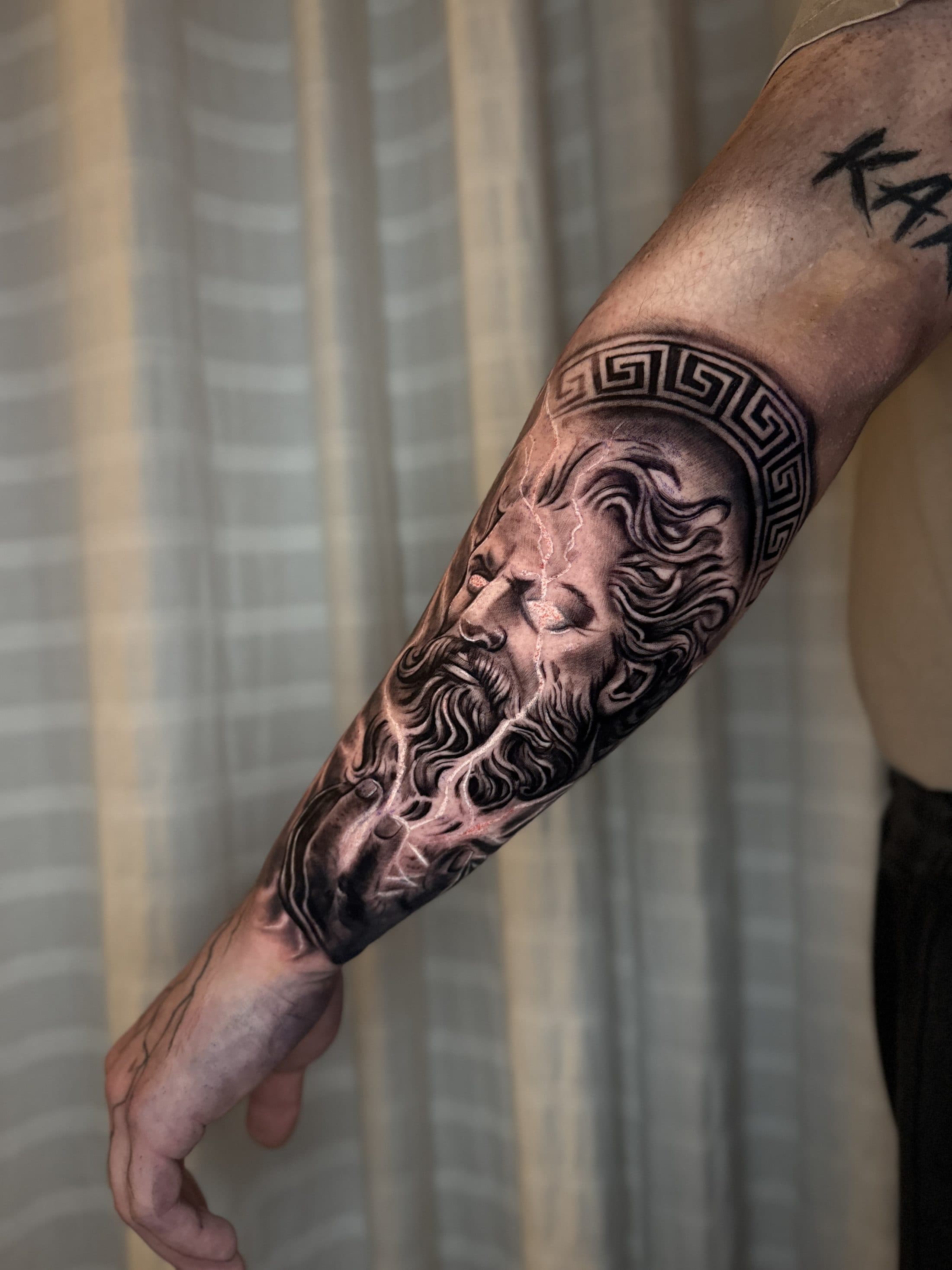 Zeus mit griechischem Mäander auf dem Unterarm